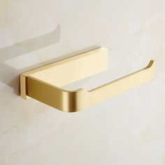 a gold toilet paper holder on a white wall