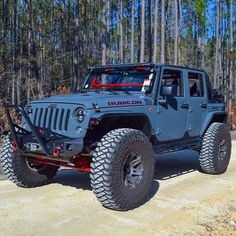 a blue jeep is parked in front of some trees