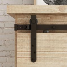 a close up of a door handle on a wooden cabinet with a brick wall in the background