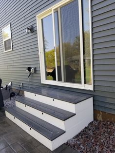 a dog is looking out the window from behind some steps in front of a house