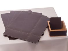 three placemats and two napkin holders on top of a white cloth covered table