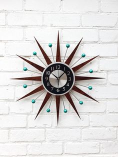 a black and brown clock on a white brick wall