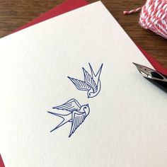 a pair of blue birds on white paper next to a red and white twine