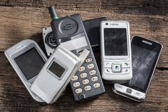 several old cell phones sitting on top of a wooden table