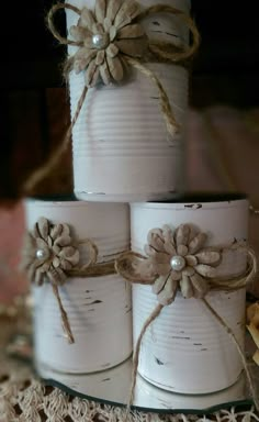 three white tin cans wrapped in twine and tied with twine, sitting on a doily