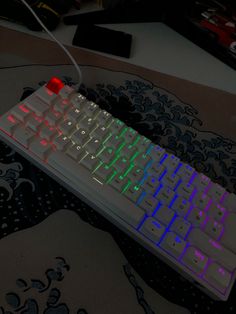 a white keyboard with red and blue lights on it sitting on a black tablecloth