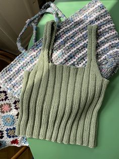 two knitted bags sitting next to each other on top of a green tablecloth