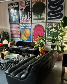 a living room filled with black furniture and lots of posters on the wall behind it