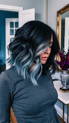 This wavy lob features a bold blue-black base with icy blue highlights framing the face. The layered waves add texture and movement, enhancing the color contrast beautifully. This style is ideal for those seeking a blend of dark tones with a touch of brightness. Blue Dye On Black Hair, Brown Hair With Dark Blue Highlights, Dark Hair Blue Highlights, Light Blue Highlights In Black Hair, Black Hair With Teal Highlights, Blue Peek A Boo Hair, Blue And Dark Brown Hair, Midnight Blue Hair Short, Dark Indigo Hair