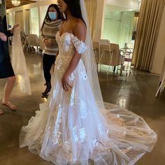 a woman in a wedding dress is wearing a face mask while another woman looks on