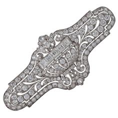 An American Art Deco platinum brooch with diamonds by E. M. Gattle & Co. The brooch has 168 old European-cut diamonds with an approximate total weight of 4.50 carats, and 5 square-cut diamonds with an approximate total weight of .75 carats. The total approximate diamond weight of the brooch is 5.25 carats, H/I color, VS clarity. The brooch centers on a dimensional jardinière flanked by pierced foliate elements with a milgrain set diamond border. Circa 1920. E.M. Gattle Co. was founded by Emanue Art Deco Diamond Brooch, American Art Deco, 1920s Jewelry, Brooch Art, Art Deco Brooch, Jewelry Antique, Gold Art Deco, Circle Diamond, 1920s Art Deco