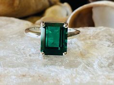 This classic 4 prong setting contains a beautiful 4.00ct. lab created emerald cut emerald. The emerald cut stone measures approximately 10x8mm. The ring is available in sterling silver, and 14k white, yellow, or rose gold. This ring makes a great promise or engagement ring. Emerald is the birthstone for May. Please send me a message if you need a size not listed. All items are handmade by me in my shop in Woodbridge, NJ. Please message me with any questions. Solitaire Emerald Ring With Radiant Cut, Radiant Cut Solitaire Emerald Ring, Emerald Cut Emerald Ring With Vvs Clarity, Green Emerald Solitaire Ring In Radiant Cut, Emerald Cut Birthstone Emerald Ring, Green Emerald Solitaire Ring With Radiant Cut, Classic Square Cut Emerald Ring With Accent Stones, Radiant Cut Green Emerald Solitaire Ring, Fine Jewelry Solitaire Emerald Ring With Rectangular Stone