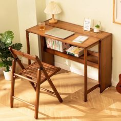 a wooden desk with a laptop computer on top of it next to a chair and potted plant