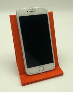 an orange cell phone holder on a white surface with the screen partially covered by leather