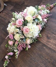 a bridal bouquet on the floor with pink and white flowers, greenery and baby's breath