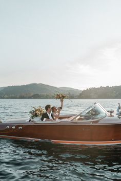 a bride and groom ride in a speedboat on the water with their bouquets