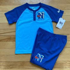 This Nike 2-Piece Graphic Set Is Perfect For Any Young Athlete Or Casual Wearer. The Set Includes A Blue Cotton Blend T-Shirt With A Graphic Logo And A Pair Of Shorts With An Elastic Waistband For A Comfortable Fit. The Shorts Also Feature A Crew Neck And Short Sleeves, Making Them Ideal For Warmer Seasons And Activities. The Set Is Machine Washable And Easy To Care For, Ensuring A Long-Lasting Addition To Any Young Boy's Wardrobe. The Nike Logo Adds A Touch Of Athletic Wear To The Outfit, While Cotton Sportswear Shorts For Playwear, Sportswear Tops For Playwear, Casual Moisture-wicking Sets For Summer, Short Sleeve Sportswear Tops For Play, Casual Summer Moisture-wicking Sets, Casual Summer Sets With Moisture-wicking, Casual Summer Sets With Moisture-wicking Details, Short Cotton Tops For Sports, Blue Cotton Short Set For Loungewear