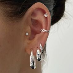 a woman wearing three different types of ear piercings