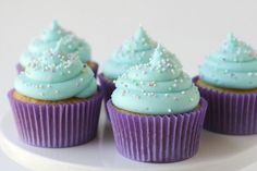 three cupcakes with blue frosting and sprinkles on them sitting on a plate