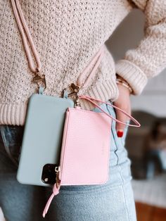 a woman holding a pink and blue cell phone case in her pocket while wearing jeans