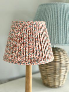 two lamps sitting next to each other on top of a white table with blue and red shades