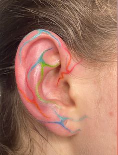 a close up of a child's ear with colored paint on it