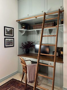 a wooden ladder leaning up against a wall next to a desk with a computer on it