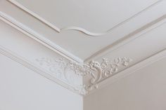 the corner of a room with white paint and decorative molding on the ceiling,