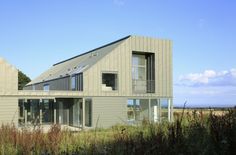 a house that is in the middle of some grass and bushes with windows on each side