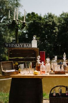 a wooden table topped with lots of bottles and glasses