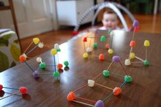 a young child sitting at a table with many pins stuck in the shape of houses