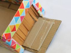 an open cardboard box with colorful geometric designs on the outside and inside, sitting on a white surface