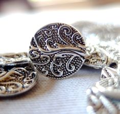 two silver rings sitting next to each other on a white tablecloth with beads and chains