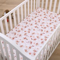 a white crib with a pink flower print on it