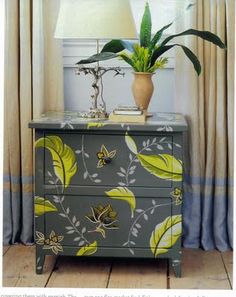 a gray and yellow painted dresser with a potted plant on it's side