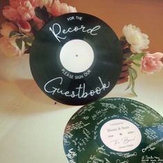 two records with writing on them sitting next to each other and flowers in the background