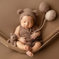 a baby sleeping in a hammock with two teddy bears attached to the side