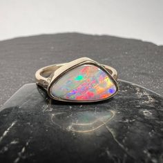 18k boulder opal ring showing red, blue and green play of color.  Bright full face boulder opal statement ring in 18k yellow gold. Ribbon pattern, please refer to video for best perspective of this stunning opal! Queensland Australian boulder opal 3.01 carats 12.73mm x 7.27mm x 3.74mm Currently US size 7 for scale (Select size at checkout) Hand made, one of kind. All of our creations are made out of 14K or 18 Gold (Yellow, White, Rose) or 925 Sterling Silver, None are filled or electroplated.  A Multicolor Opal Multi-stone Rings, Multicolor Opal Gemstone Ring, Multicolor Opal Ring, Opal Statement Ring, Green Play, Ribbon Pattern, Boulder Opal Ring, Gem Shop, Australian Boulder Opal