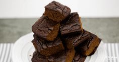 a stack of brownies sitting on top of a white plate next to a fork