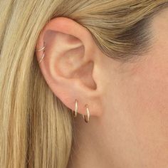 a close up of a woman's ear with two small hoops on it