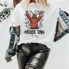 Rock On T-Shirt, Rocker shirt, Rodeo fan gear, Rodeo Kids, Brahman Darlin, NFR Fashion, NFR Afterparty, NFR number on back shirt, Buckle Bunny tee Thank you for shopping my small business. Please message me if you have questions. This is a physical shirt that is made when you order it and shipped out to you. If you love the design and would like it on a different type of item, rather message me and I will do what I can to get a different product to you. Shipping times are 2-5 days, but the longe Unisex Rocker T-shirt For Concerts, Rock Style Crew Neck T-shirt For Music Festival, Rock Style Crew Neck T-shirt With Screen Print, White Rocker T-shirt With Graphic Print, Short Sleeve T-shirt For Music Festival In Fall, White Rocker Graphic Print T-shirt, White Rocker Style Graphic T-shirt, Punk Style Graphic T-shirt For Fall, Rock Style Short Sleeve T-shirt For Fall