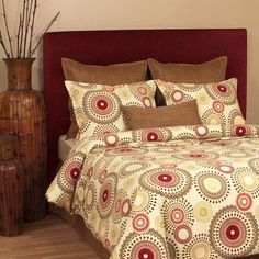 a bed with a red headboard and pillows on top of it next to a vase