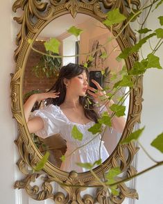 a woman taking a selfie in front of a mirror with ivy growing on it