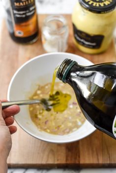 someone is pouring mustard into a white bowl