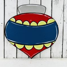 a red, yellow and blue heart shaped sign on a white wooden wall