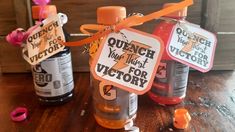 three bottles with orange and pink ribbons tied to them on a wooden table next to each other