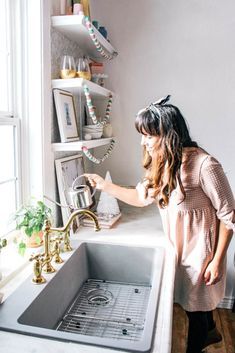 a woman standing in front of a kitchen sink