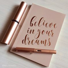 a notebook with the words believe in your dreams on it next to a fountain pen