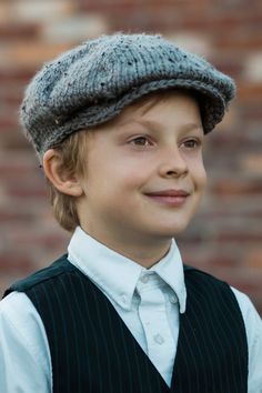 a young boy wearing a hat and vest