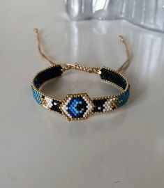 a beaded headband with an evil eye on the front and back ends is sitting on a table